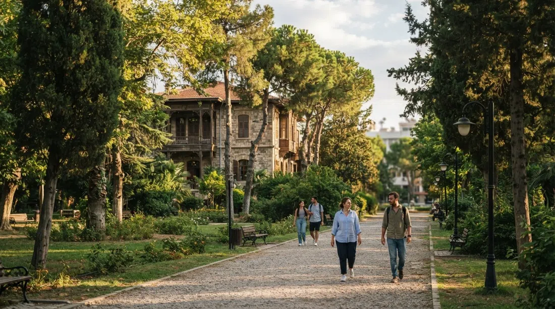 Los jardines sombreados de cipreses del Rectorado de la Universidad Ege en Bornova, con la Casa Grande Whittall al fondo entre árboles en la luz de la tarde